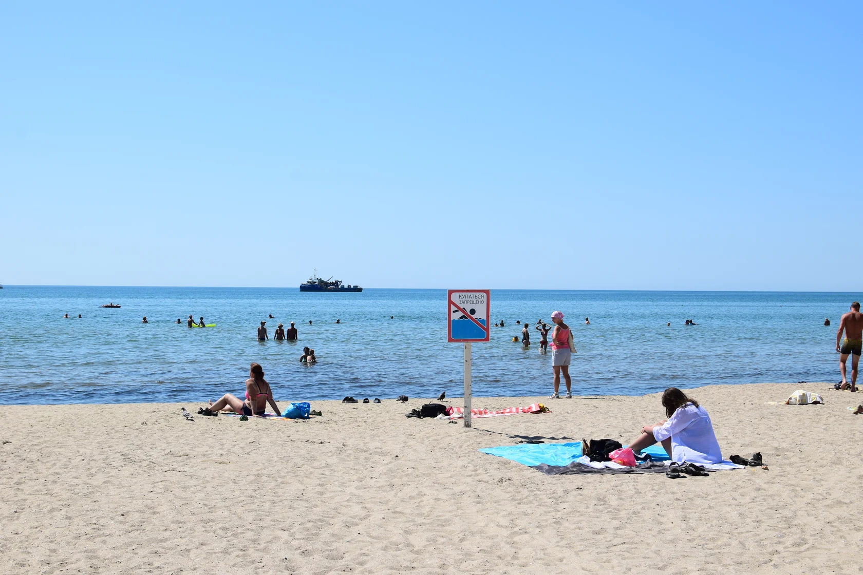 Пляж в Анапе в июле 2025. Знак Купаться запрещено, люди купаются.